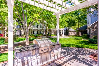 a backyard with a grill and a white pergola
